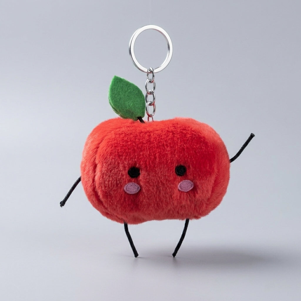 A red junimo keychain with a green leaf, embroidered eyes and cheeks, and black wire arms and legs, attached to a silver metal key ring on a light gray background.