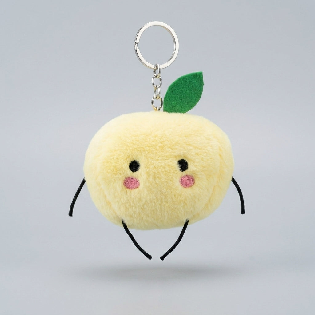 A cute yellow plush keychain shaped like a Junimo , with a green felt leaf, embroidered face, black limbs, and a silver metal key ring on a light gray background.