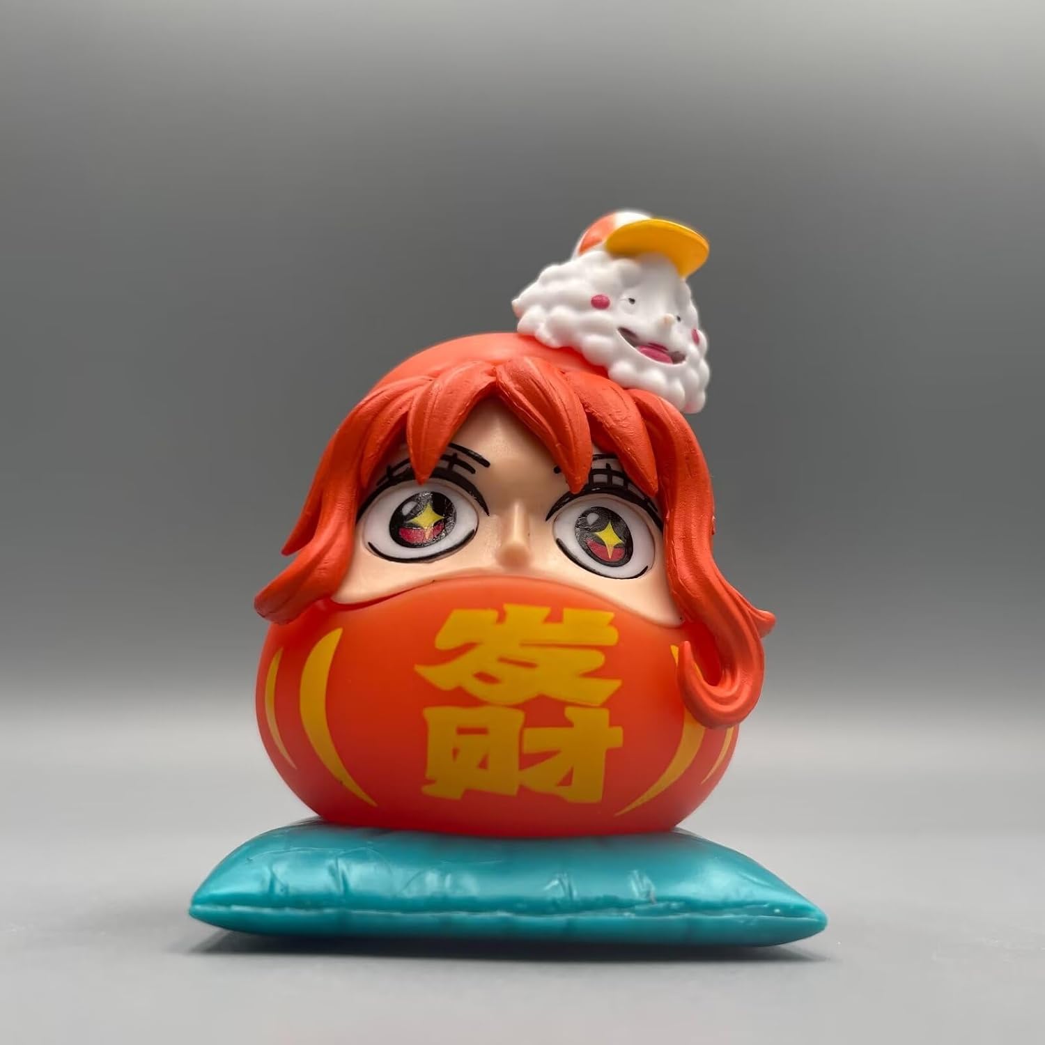 One Piece Daruma figurine of Nami, featuring orange hair, starry eyes, and a red Daruma body with a blue cushion.