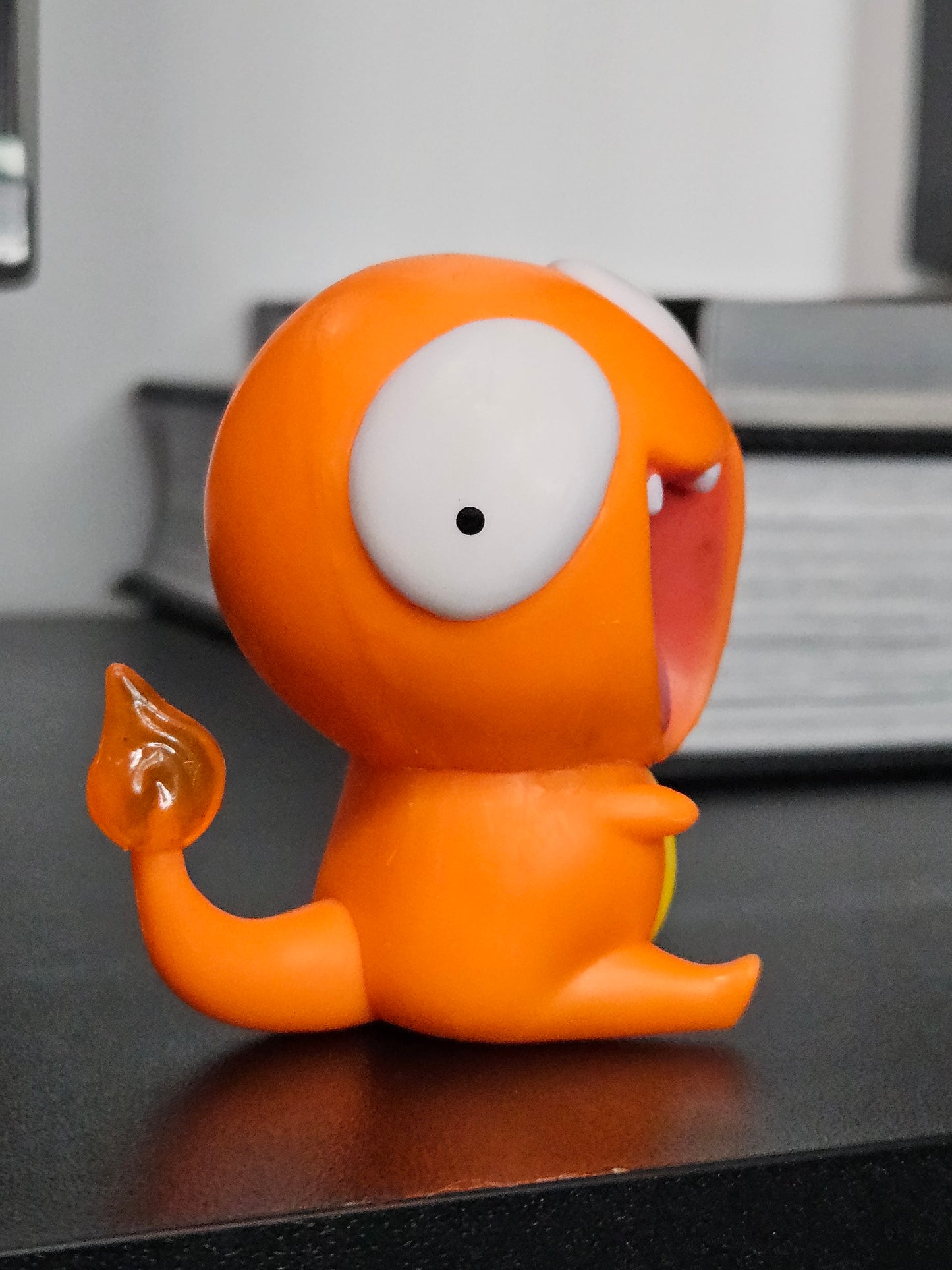 Side view of a funny Charmander figurine featuring a derpy expression, wide eyes, and a flaming tail, showcasing its playful and humorous design for collectors and fans alike