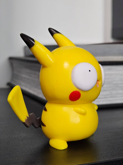 Side view of a funny Pikachu figurine with derpy wide eyes, red cheeks, and its signature lightning bolt tail, showcasing a playful and quirky take on the beloved Pokémon character