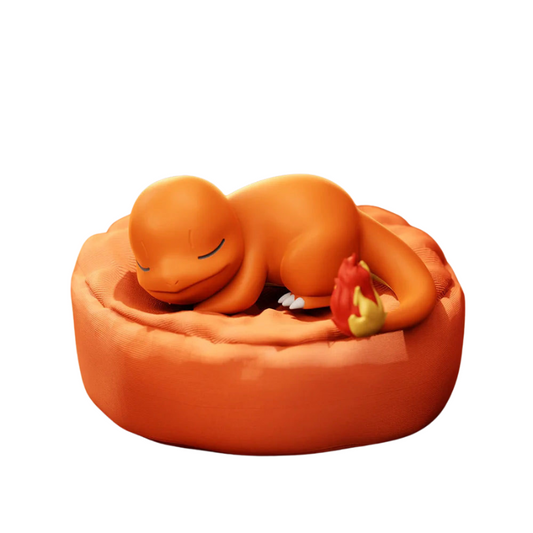 Pokémon figurine of Charmander sleeping on an orange cushion with an apple by its tail.